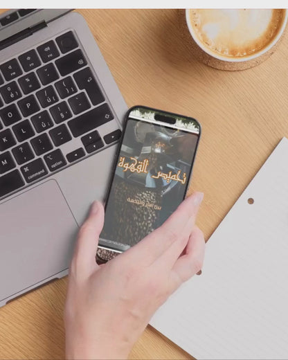 كتاب إلكتروني بعنوان تحميص القهوة | تعلم اسرار وكيفية تحميص القهوة للمبتدئين معروض على هاتف بجانب لابتوب وفنجان قهوة. مثالي لعشاق القهوة ومحبي التعلم الرقمي.